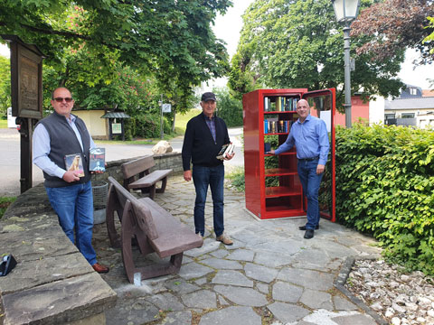 Hans Dieter Geiger (1.Beigeordneter), Rolf Kahmann (Vorsitzender SPD-Fraktion), Martin Buchholz (Ortsbürgermeister) bei der Inbetriebnahme des neuen Bücherschranks. Bildquelle: Ortsgemeinde Windhagen